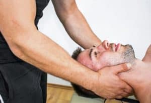 . Personal trainer working on a man's neck as part of a rehabilitation therapy